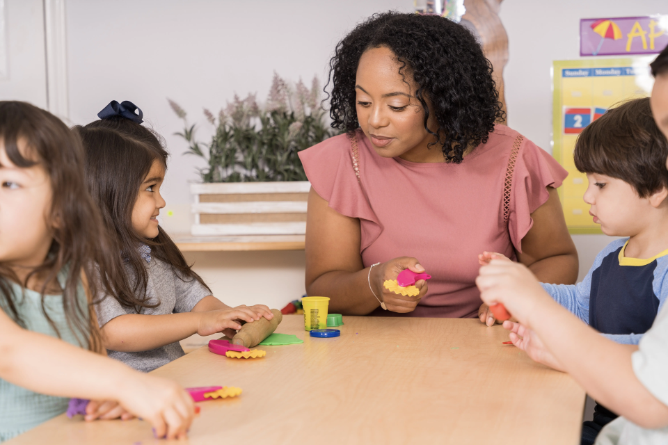 Teacher with pink shirt playing with children with playdoh